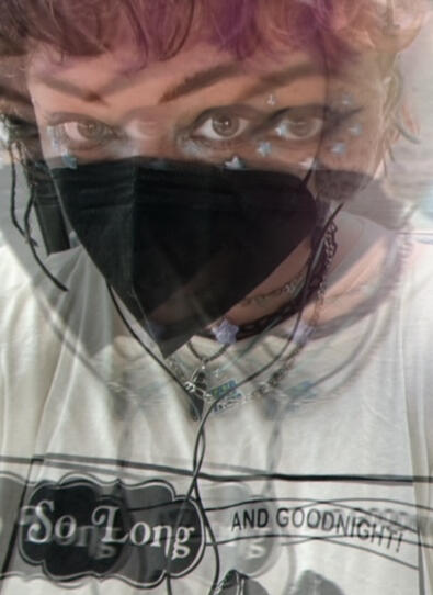 photo of tuesday, a white nonbinary person in their mid-20s wearing a black KN95 mask, headphones, and dramatic eye makeup. they are wearing a tshirt that reads 'so long and goodnight'. the photo is edited to look blurry and trippy.